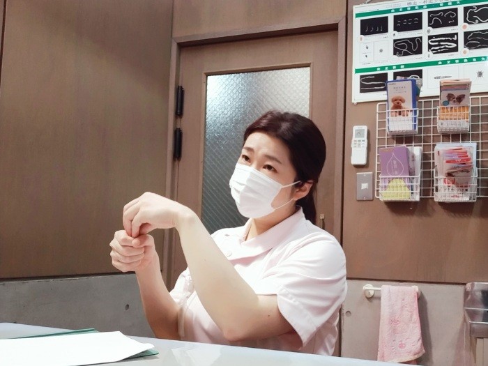 握りこぶしの上に指を差し込む手話で「便秘」（！）を表現する小原さん（小原さん提供）