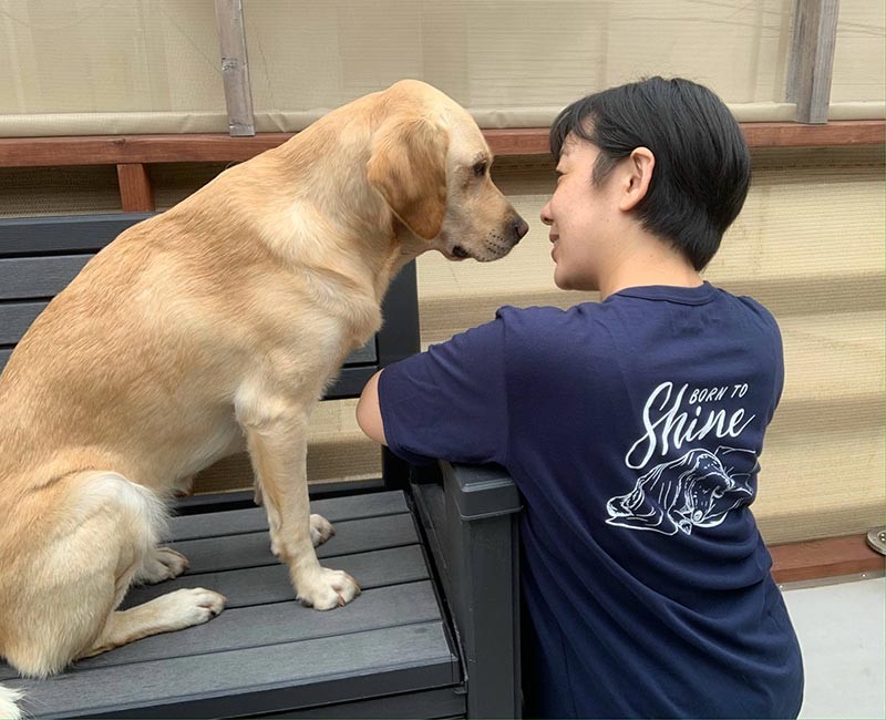 こちらは紺バージョン。モデルは東京都立小児医療センターのファシリティドッグ「アイビー」とハンドラーの大橋真友子さん