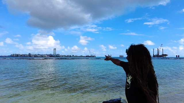 モルディブの首都マレ島を指さす、隣島ビリンギリの環境NGO代表ハッサン・ベイベ・アフメドさん＝2023年12月19日、荒ちひろ撮影
