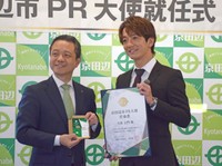昨年４月に開かれた京田辺市ＰＲ大使の就任式で、上村崇市長（左）から任命書を受け取る大倉士門さん＝同市興戸・京田辺クロスパーク
