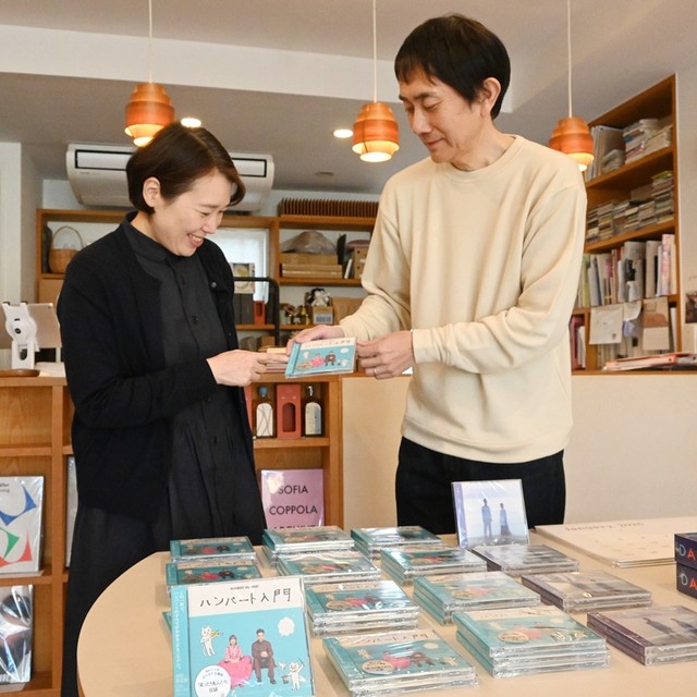 松江で初めてライブした会場のアルトスブックストアで、ハンバートハンバートのアルバムを手に取る西村史之店主（右）夫婦＝島根県松江市南田町