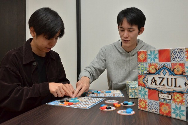 共同運営する学生にボードゲームのルールを教える稲垣さん。利用客にルールを正確に分かりやすく説明するのも、ボードゲーム店の重要な業務の一つ