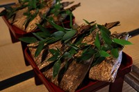 稚児餅を１０串ずつ束ねて竹皮で包み、笹の葉を添えて朱塗りの神膳に盛って本殿に供えます（提供：中村楼）