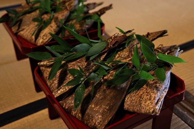 稚児餅を１０串ずつ束ねて竹皮で包み、笹の葉を添えて朱塗りの神膳に盛って本殿に供えます（提供：中村楼）