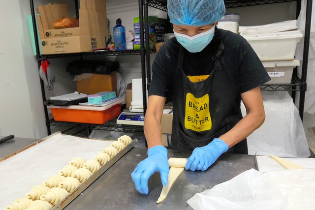 クロワッサンの形にパン生地を巻くマドゥさん=2021年2月3日、シドニー、小暮哲夫撮影
