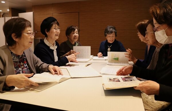 ノートを見て思い出話で盛り上がる村上さん（左から２人目）や松井さん（左）たち＝京都市下京区のホテル