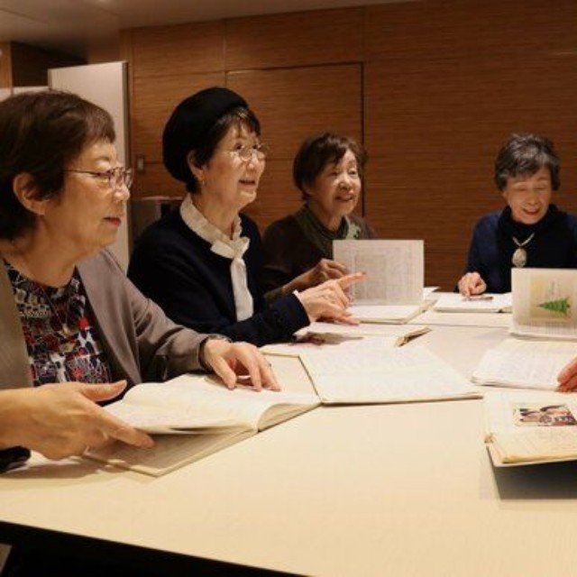 ノートを見て思い出話で盛り上がる村上さん（左から２人目）や松井さん（左）たち＝京都市下京区のホテル