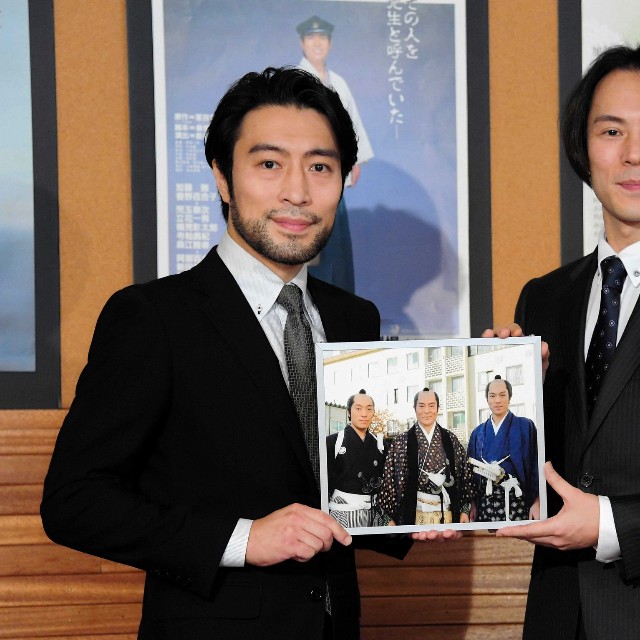 「大岡越前」で共演した父・加藤剛さんとの思い出の写真を手にする次男・加藤頼（左）と長男・夏原諒＝2018年