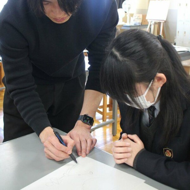 ペンを手に生徒に人物の描き方をアドバイスする世津田さん
