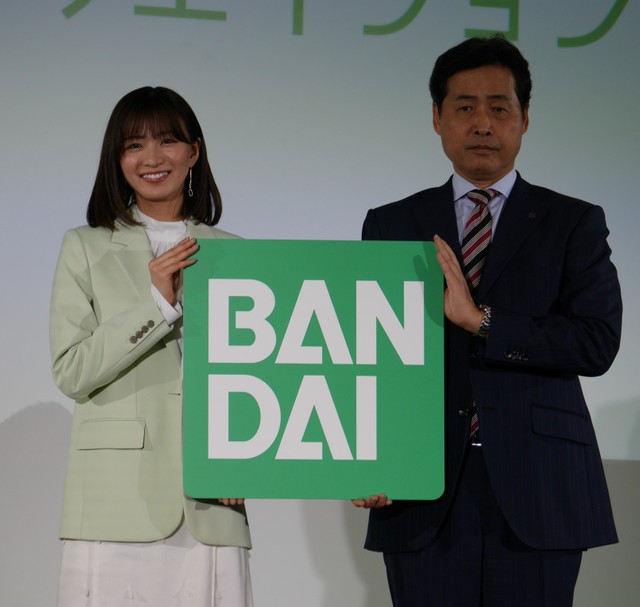 「未来・クリエイション」のキャンペーンボードを掲げる岡崎紗絵（左）、バンダイの竹中一博社長＝東京・台東区