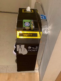 玄関に設置された「ダンボールの改札」。紙の切符を差し込んだ場合、自動で排出されないため、切符の排出部分に「ティッシュケース」を設置（画像提供：ダンボールビーダマン工作・発明 さん）