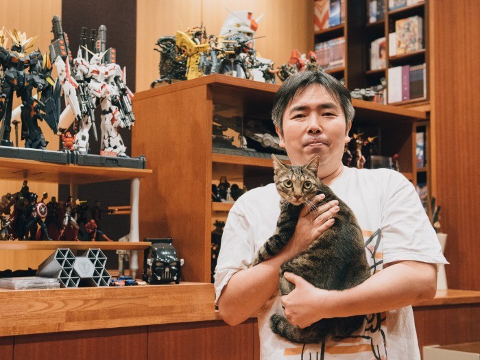 ずらりと並んだガンプラやフィギュアの前で。愛猫の１匹ドーナツ君と