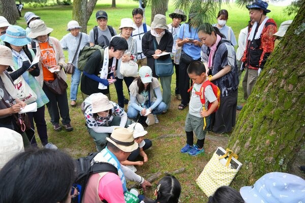 世話役の佐野さん（中央下）の解説を受けながらキノコを観察する参加者ら＝６月２２日、京都御苑