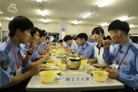 警察学校の学生と昼食を取りながら談笑する記者（右から２人目）