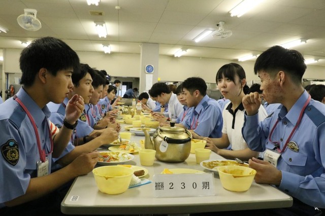 警察学校の学生と昼食を取りながら談笑する記者（右から２人目）