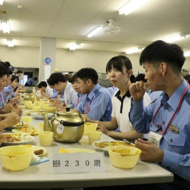 警察学校の学生と昼食を取りながら談笑する記者（右から２人目）