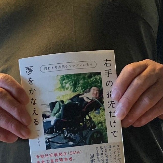 息子の自伝的書籍を持つ、ウッディさんの父