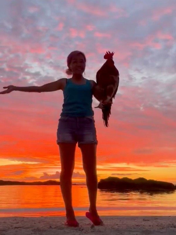 夕焼けを背景にツーショット！ ぴあやのさんの腕にのったピヨちゃん（画像提供：ぴあやの 島暮らしピアノ弾きさん）