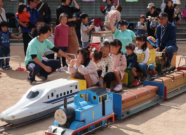 手作りのミニ列車で子どもたちを楽しませる奥村さん（右端）。後方から見守る＝２０１８年、亀岡市内