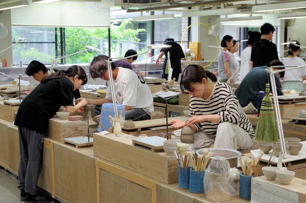 ろくろの前であぐらをかき、碗作りを反復練習する訓練生たち（京都市東山区・府立陶工高等技術専門校）