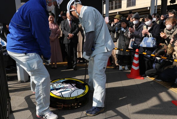 多くのファンが見守る中、行われた成瀬あかりを描いたマンホールのふたの設置作業（大津市馬場２丁目）