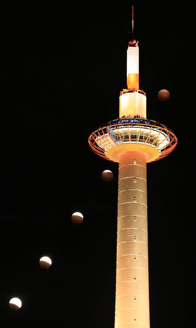 京都では2014年にも皆既月食が見られた。京都タワーの背後で赤銅色に変わる月（2014年10月８日午後６時３５分から７時３５分の間に撮影した５枚を合成、京都市下京区）