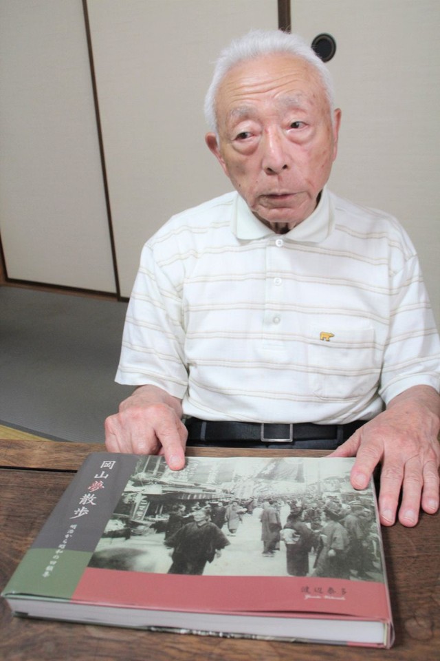 「岡山夢散歩」を手に「戦前の商店街などの写真を見て当時の暮らしを感じてほしい」と話す渡辺さん