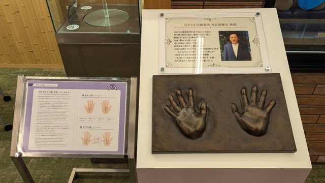 創業者・⻆谷建耀知氏の略歴と手形。両手には“天下取りの相”ともいわれるますかけ線がくっきりと。 ※筆者撮影