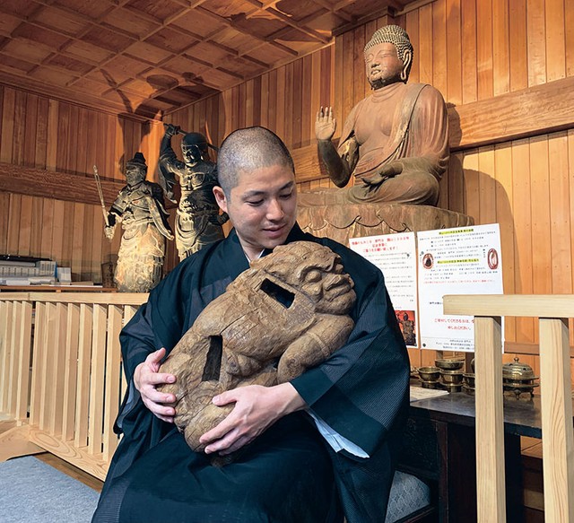 安らかな表情を浮かべる邪鬼を抱っこする林義将住職（愛知県豊橋市・普門寺）＝提供写真