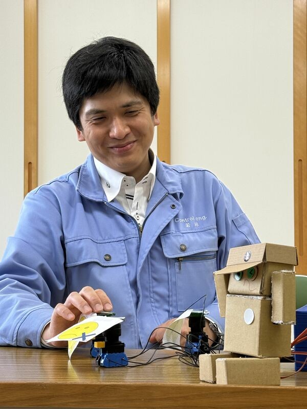 学生らと作ったコミュニケーションロボットの操作を確かめる舞鶴高専の若林准教授