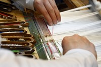 作品の表面保護と裏側から糸の通り具合を調整するために、裏織りをします。こちらは「威毛錦」を織っています（2026年7月撮影）