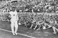 ベルリン五輪男子マラソンで2時間29分19秒の五輪新記録を出して金メダルを獲得した孫基禎選手。表彰式後にドイツ青年の祝福を受け、オークの鉢植えを手に疲れ切った表情でグラウンドを歩いた