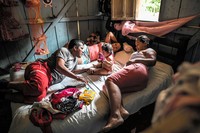 Jairo and Dayana have his sister Liliana staying with them for a few days. Their father was a campesino who lived off the land by growing coca leaves. While the FARC have gone back to farming, they are not allowed to grow coca, even though it is much more profitable than other crops, and is easy to grow in the jungle. Jairo and Dayana grow corn for their hens, plantain bananas for their pig, and have a small vegetable garden.Jairo et Dayana re腔ivent la visite de Liliana, la sﾏur de Jairo, pour quelques jours. Leur p俊e 師ait campesino (paysan) et vivait de la culture de feuilles de coca. Les FARC qui reviennent
