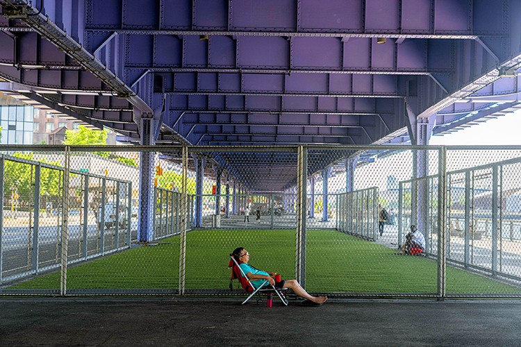 A man cools off under an overpass in Manhattan during a summer heatwave on Wednesday July 20, 2022. Water bottles, with sweating beads of condensation, water guns, spraying in parks and inside apartments and fire hydrants transforming into sprinklers. These are some of the tools New Yorkers are using to work and play during the summerﾕs first heat wave, as daily temperatures near 100 degrees. (Hiroko Masuike/The New York Times)