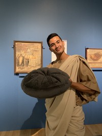 モデル・AMONさん扮する「＃ポンペイくん」と「炭化したパンのクッション」　（提供・特別展「ポンペイ」）