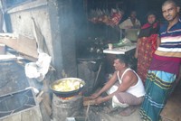 ダッカ市内のスラムにある店でシンガラ（サモサに似た揚げ物）を作る男性。スラム内にもガスが供給されているが、この区域にはパイプが届いていないため、薪を使って調理しているという=2024年5月3日、荒ちひろ撮影