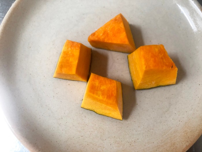 カボチャは皮付きのまま2.5cm程度の角切りにし、耐熱皿に並べる。ラップをかけて電子レンジに2分程度かけやわらかくする。