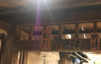 長屋の入り口にある表札。「松野」、傘屋の「折笠」、トキの幼なじみ・サワ（円井わん）の家「野津」の表札もある