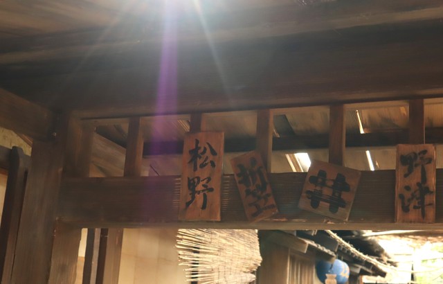 長屋の入り口にある表札。「松野」、傘屋の「折笠」、トキの幼なじみ・サワ（円井わん）の家「野津」の表札もある