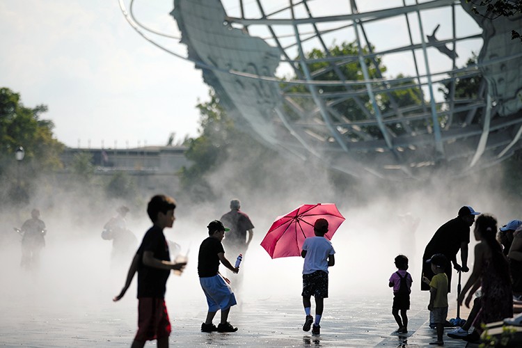 Residents cool off at the Flushing Meadows Corona Park fountains as record high temperatures hit New York City on July 20, 2022. Water bottles, with sweating beads of condensation, water guns, spraying in parks and inside apartments and fire hydrants transforming into sprinklers. These are some of the tools New Yorkers are using to work and play during the summer's first heat wave, as daily temperatures near 100 degrees. (Jose A. Alvarado Jr./The New York Times)