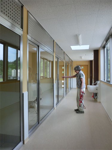 篠山アークの犬舎の廊下に立つオリバーさん。ガラス越しに犬たちの姿を見ることが出来る（アニマルレフュージ関西提供）