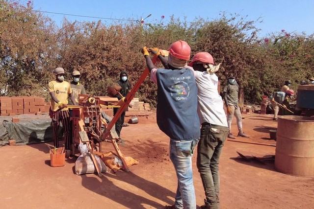 人力の圧縮機械を使い、土れんがをつくる「エレメンテール」の作業員ら＝2023年12月23日、セネガル西部、荒ちひろ撮影