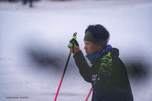 雪上でスキーをしている森宏明。両手にスキーポールを持ち、黒いウェアと蛍光色の手袋を着用。背景は雪に覆われた広いフィールド。