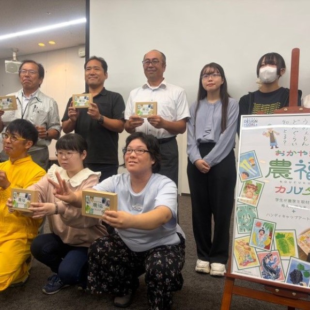 カルタの完成を喜ぶアーティストや、制作に協力した農畜水産業者ら＝岡山市北区駅元町