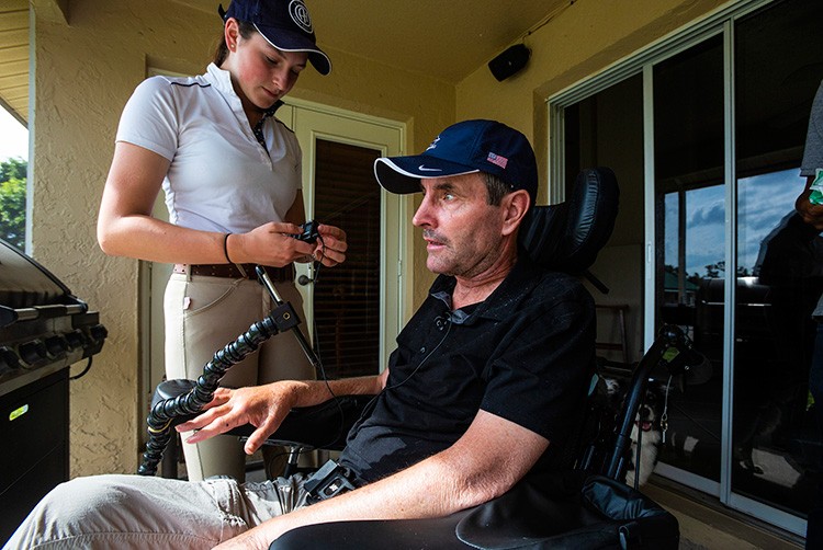 FILE -- Kevin Babington an Irish Olympian show jumper, who injured his spinal cord in a show jumping accident, gets help from his  his daughter Marielle with a listening device as he is gives a lesson at their home in Loxahatchee, Fla., last year on Jan. 30, 2020. In the summer of 2019, he was paralyzed from the chest down after being flung from his horse, Shorapur, at the Hampton Classic, a prestigious horse show in Bridgehampton, N.Y. (Saul Martinez/The New York Times)