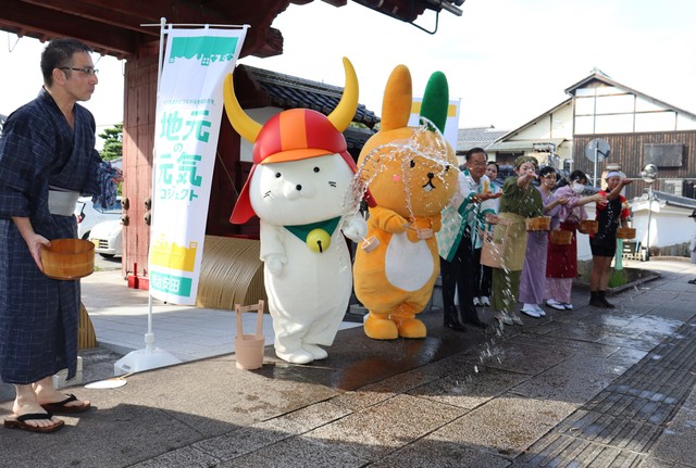 「夢京橋キャッスルロード」で打ち水をするひこにゃん（２０２４年７月、彦根市本町２丁目）