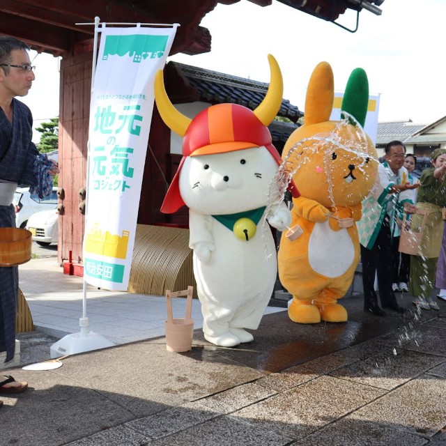 「夢京橋キャッスルロード」で打ち水をするひこにゃん（２０２４年７月、彦根市本町２丁目）