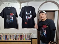 「ブラック・エンジェルズ」の決めゼリフ「地獄に落ちろ」がプリントされたＴシャツを前にポーズを決める平松伸二氏＝東京・・浅草の「漫画ギャラリーＣＡＦＥ　オカオカ」