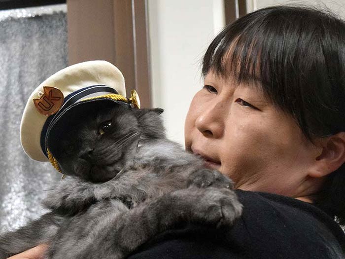 「駅長」の制帽をかぶったしょこらと細谷さん