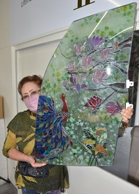 車の窓ガラスを活用したグラスアートを持つ今川美知代取締役。廃車の一部も、使い方によっては美しいインテリアに変わる